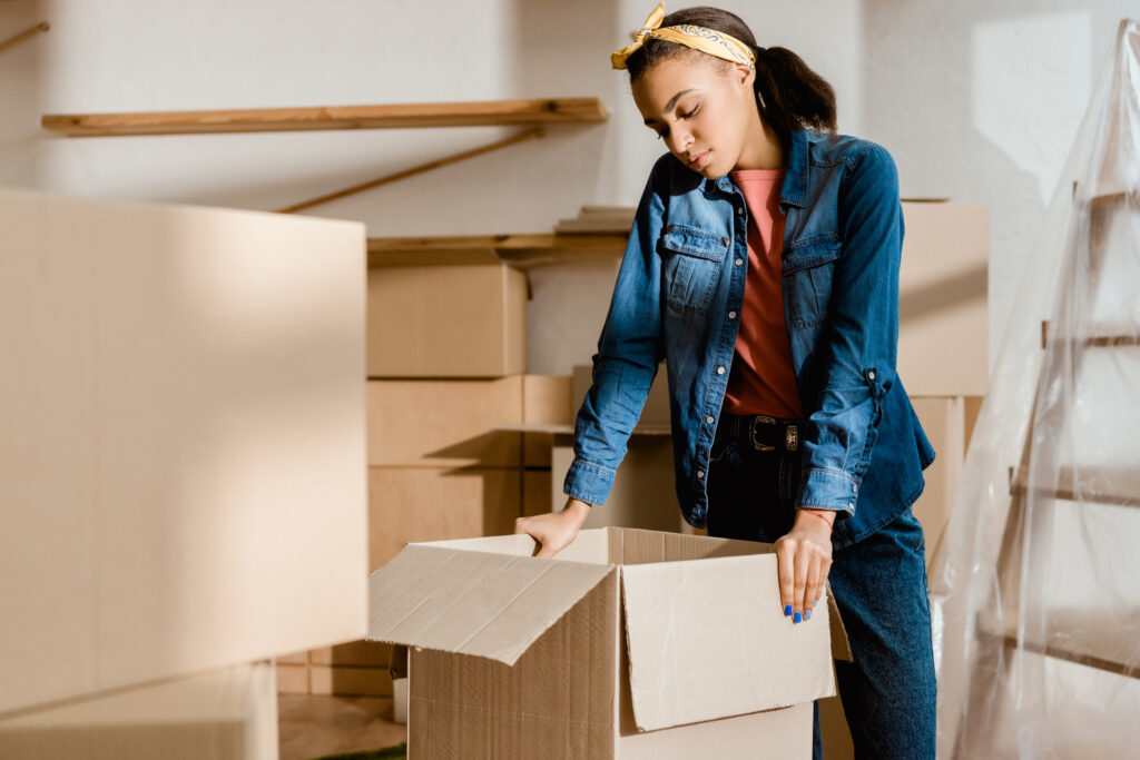 an upset teen is packing a box because her family is moving