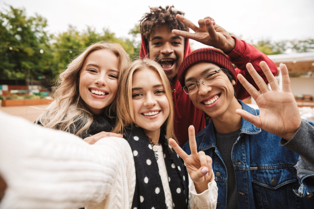 A group of teens dressed in winter apparel, smiling and posing for a photo