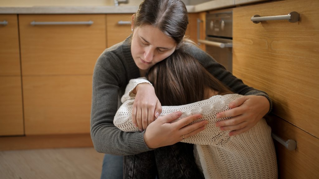 Young mother comforting her suicidal daughter and talking about treatment.