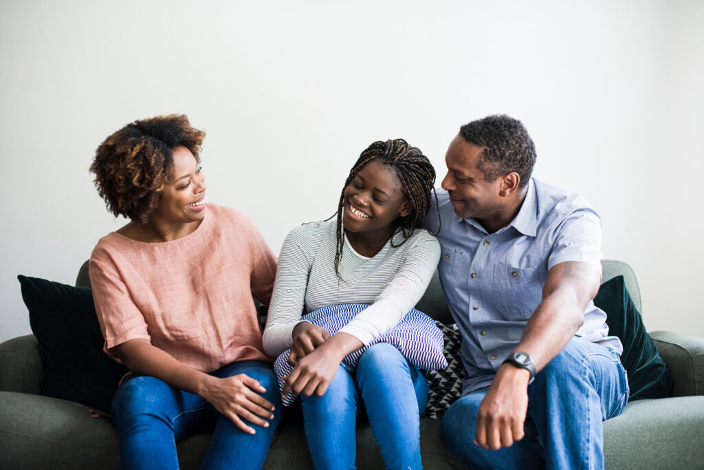 two happy parents sit with their teen after learning to divide parenting roles