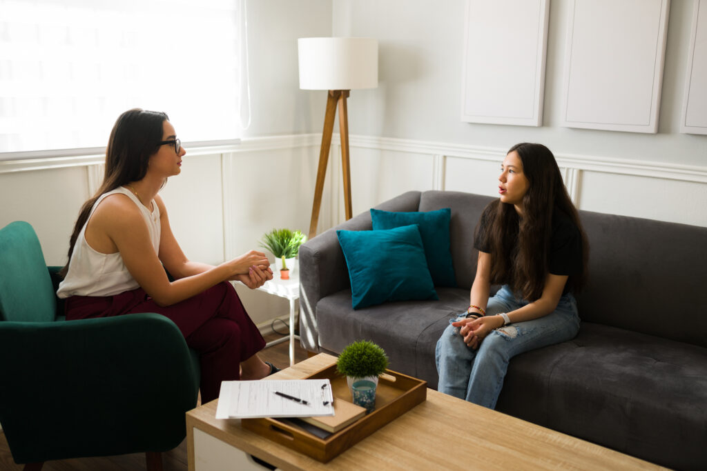 a depressed teen sits in a residential treatment office talking to a therapist