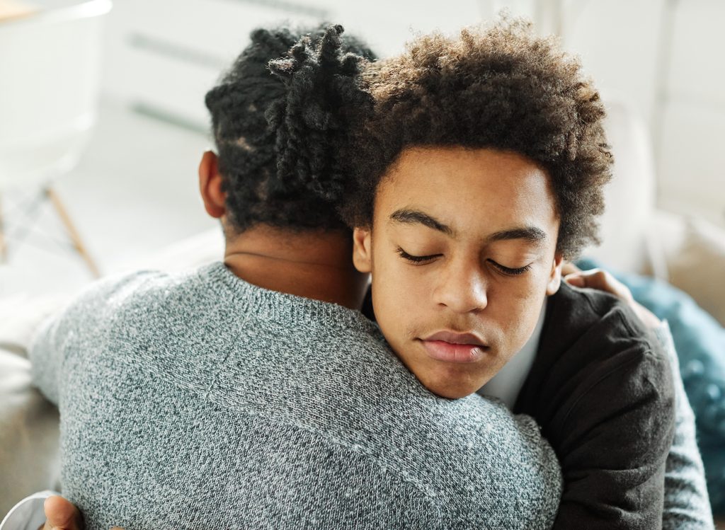 Father hugs son in support son while talking about self-harm treatment.