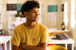 Smiling teen boy in high school classroom is happy after using DBT skills