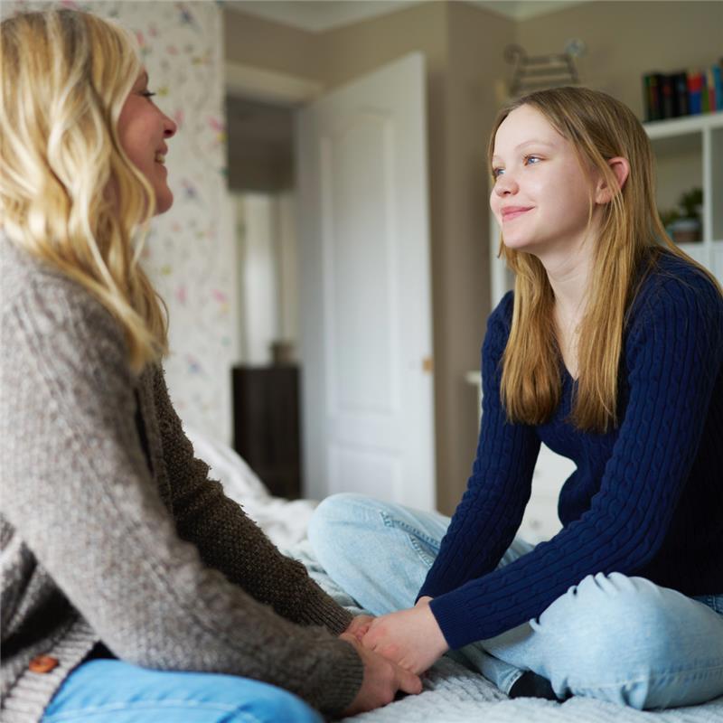 A mother holding her daughters hands offering support