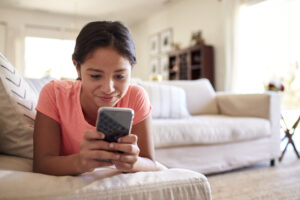 teen girl surfing phone on couch