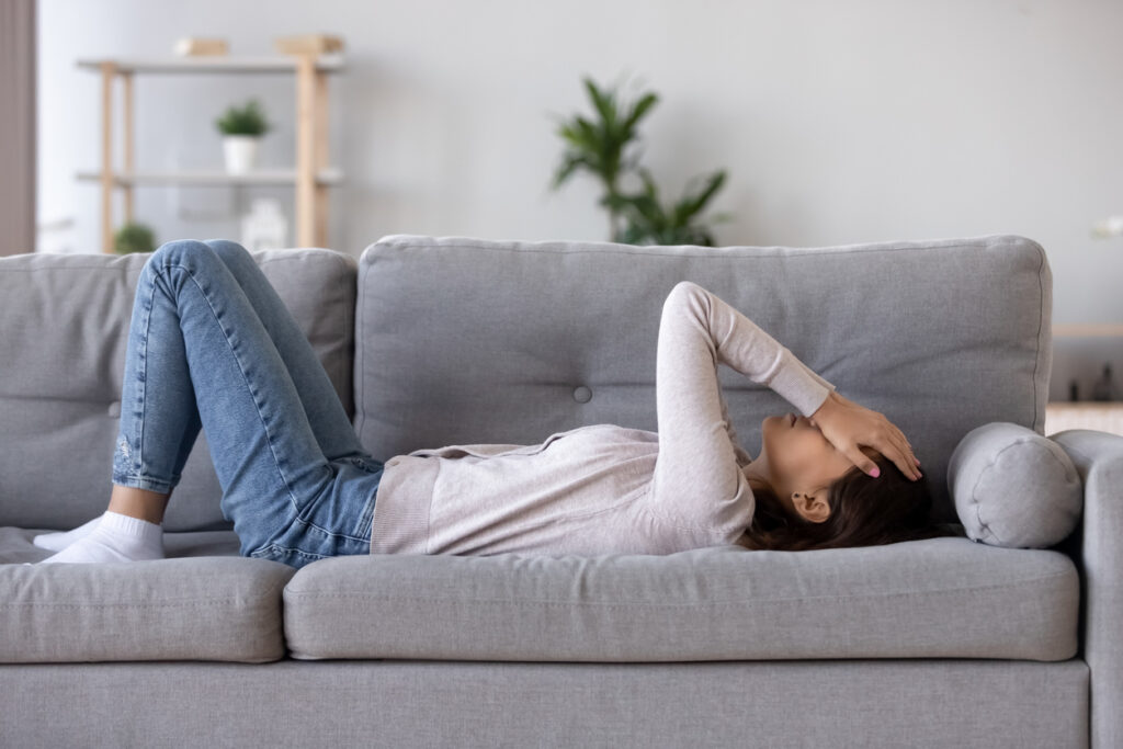 teen lying on couch covering eyes