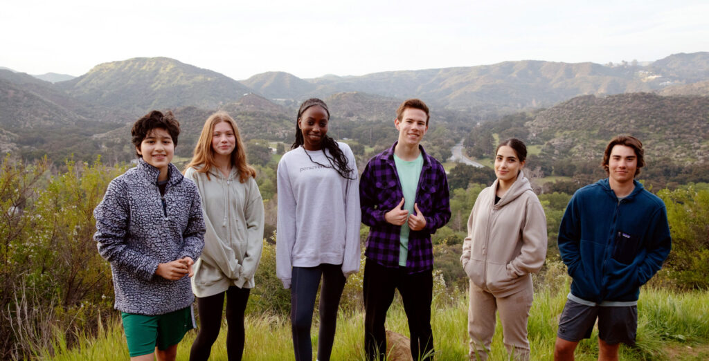 Teens from residential treatment smile and pose for a picture at the top of a hike.